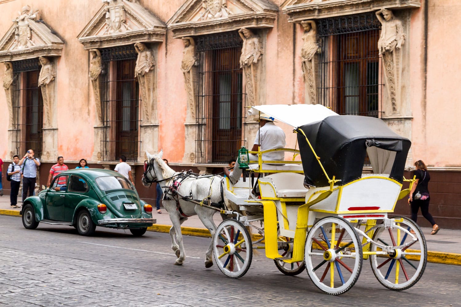 Carrozze a cavalli con passeggeri su una strada cittadina a Merida in Messico.